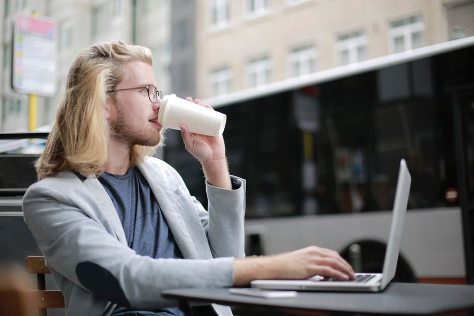 Freelancer muda bekerja remote sambil menikmati kopi — konteks nerima gaji dolar dan ngatur rekening USD dari rumah